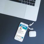 Das Bild zeigt einen Laptop, neben dem ein Handy liegt. Darauf ist ein LinkedIn Profil geöffnet.